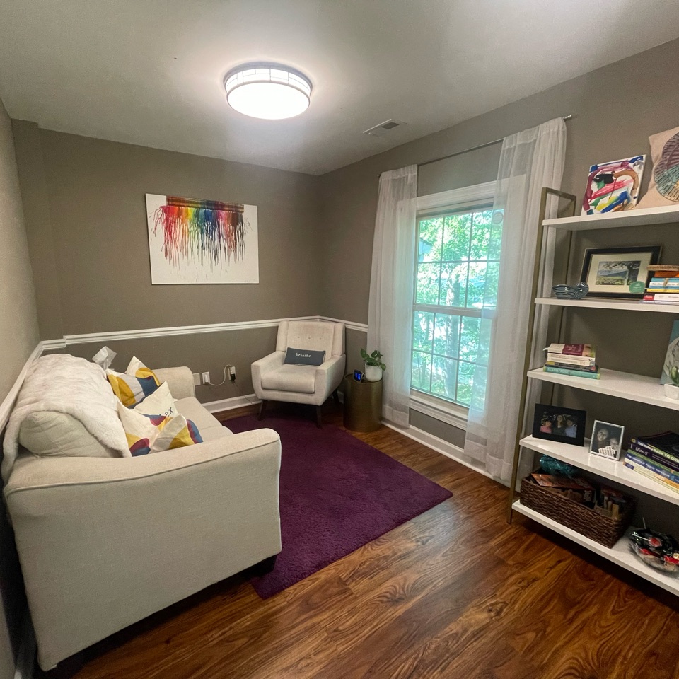 Quinn’s therapy office with a white couch, armchair, and bookshelves